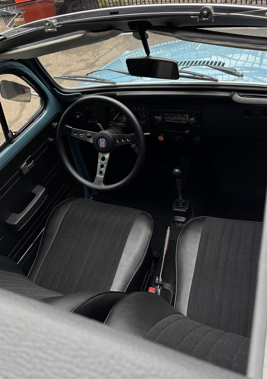 Interior de Fusca azul com bancos pretos e volante esportivo